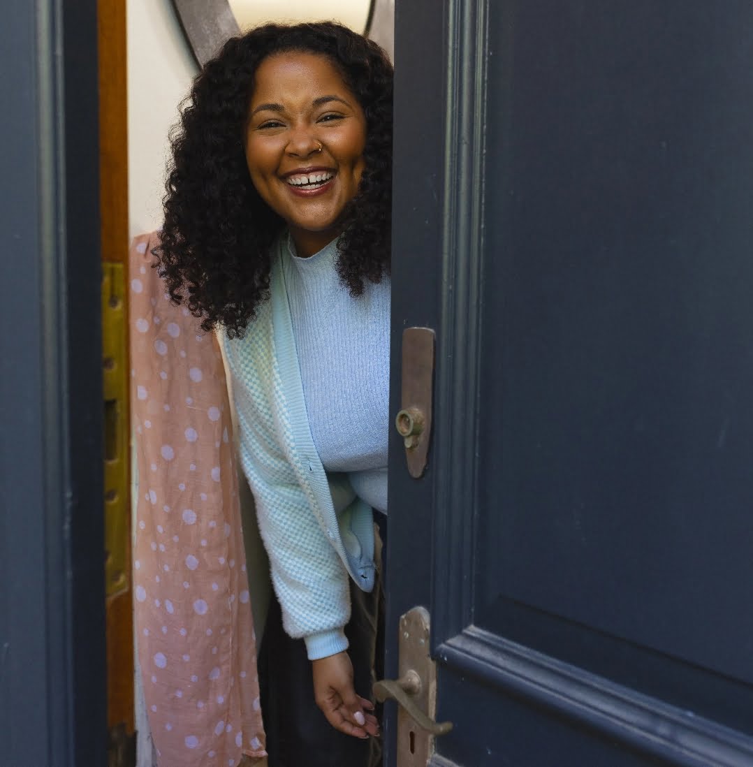 Smiling woman opens door to apartment; BFNC Housing programs, licensed community residences