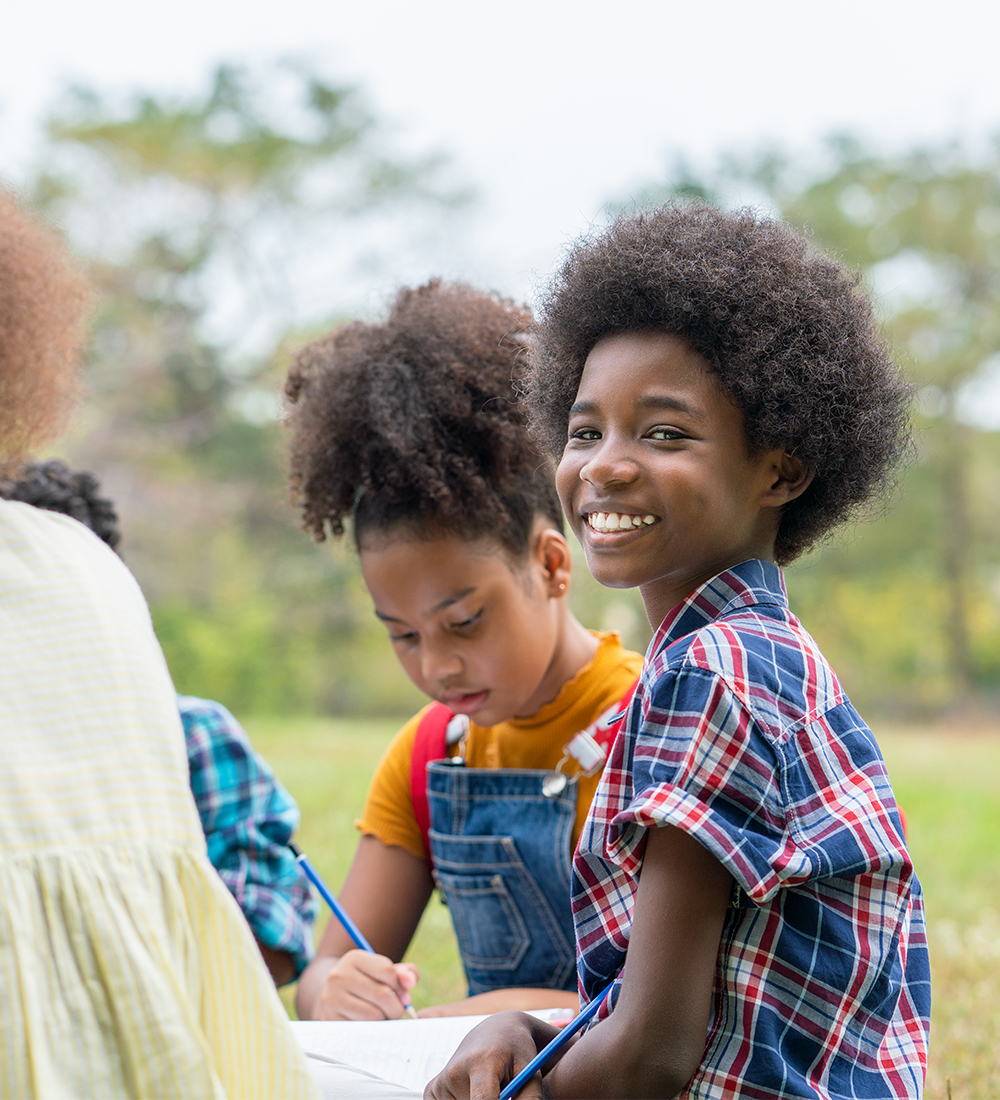 Circle of children doing homework outside; Niagara County Youth Services, BFNC Youth programs